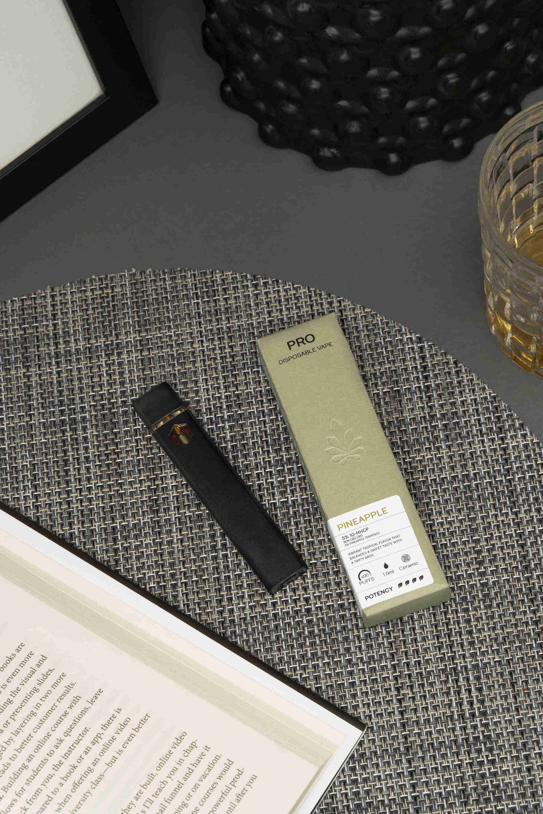 Nine Realms PRO THC Vape on the table wit a book and drink nearby