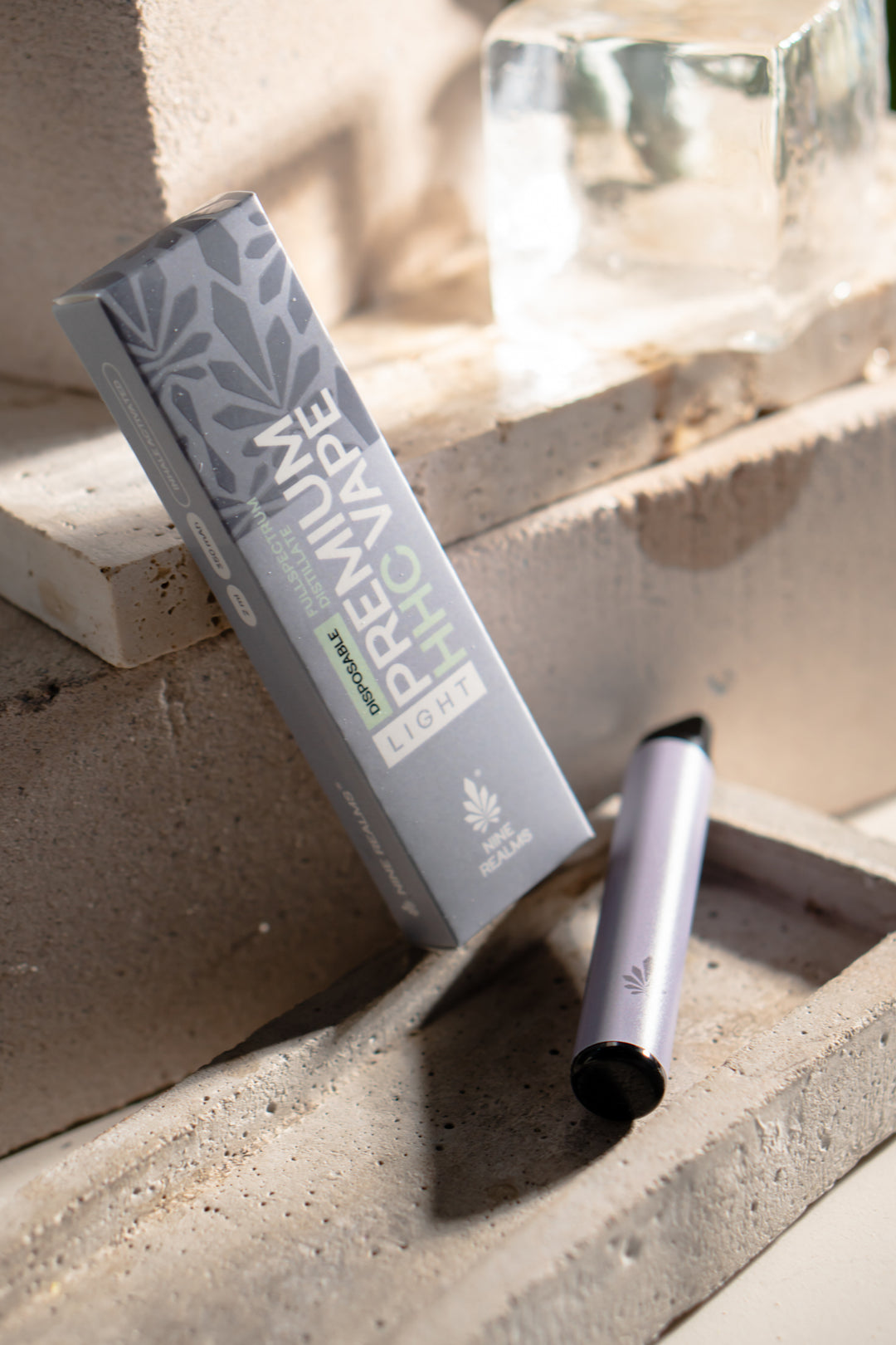 nine realms premium hhc vape and packaging in a natural artistic composition of concrete