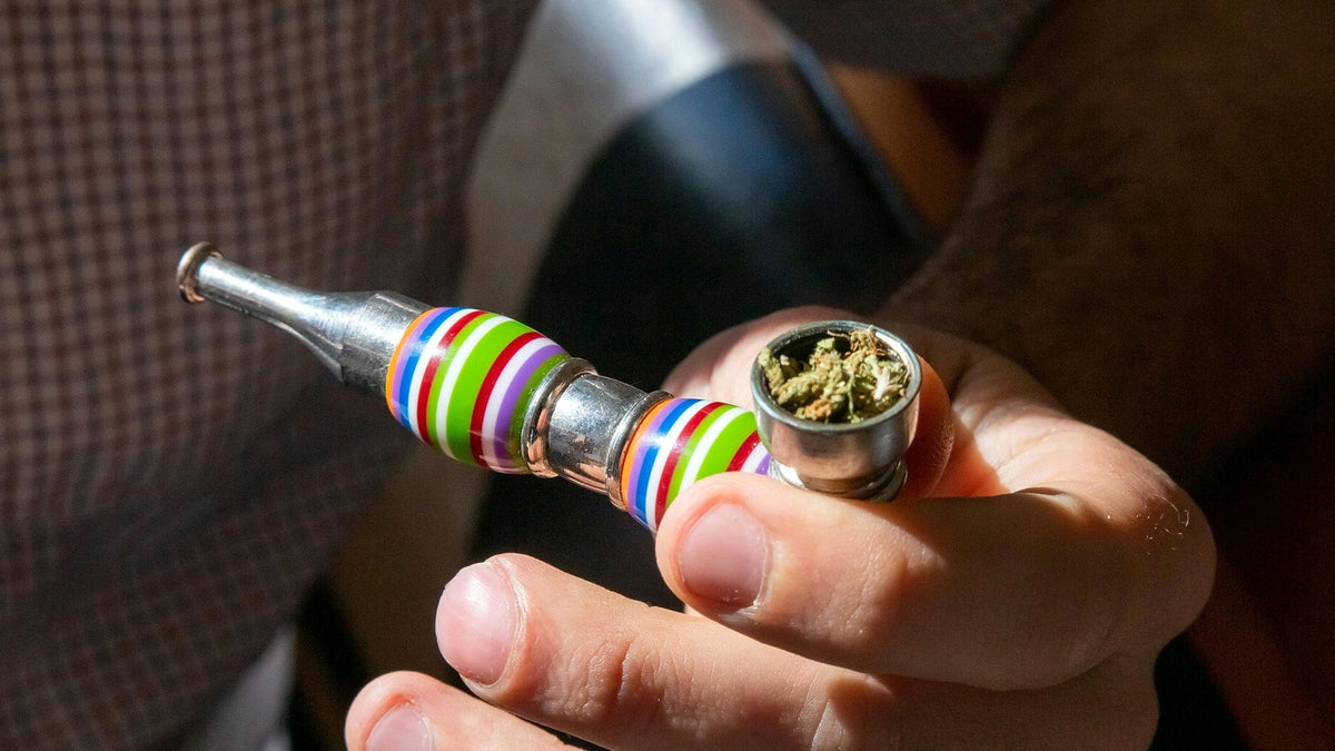 Man holding Nine Realms 10-OH-HHC flower in a pipe