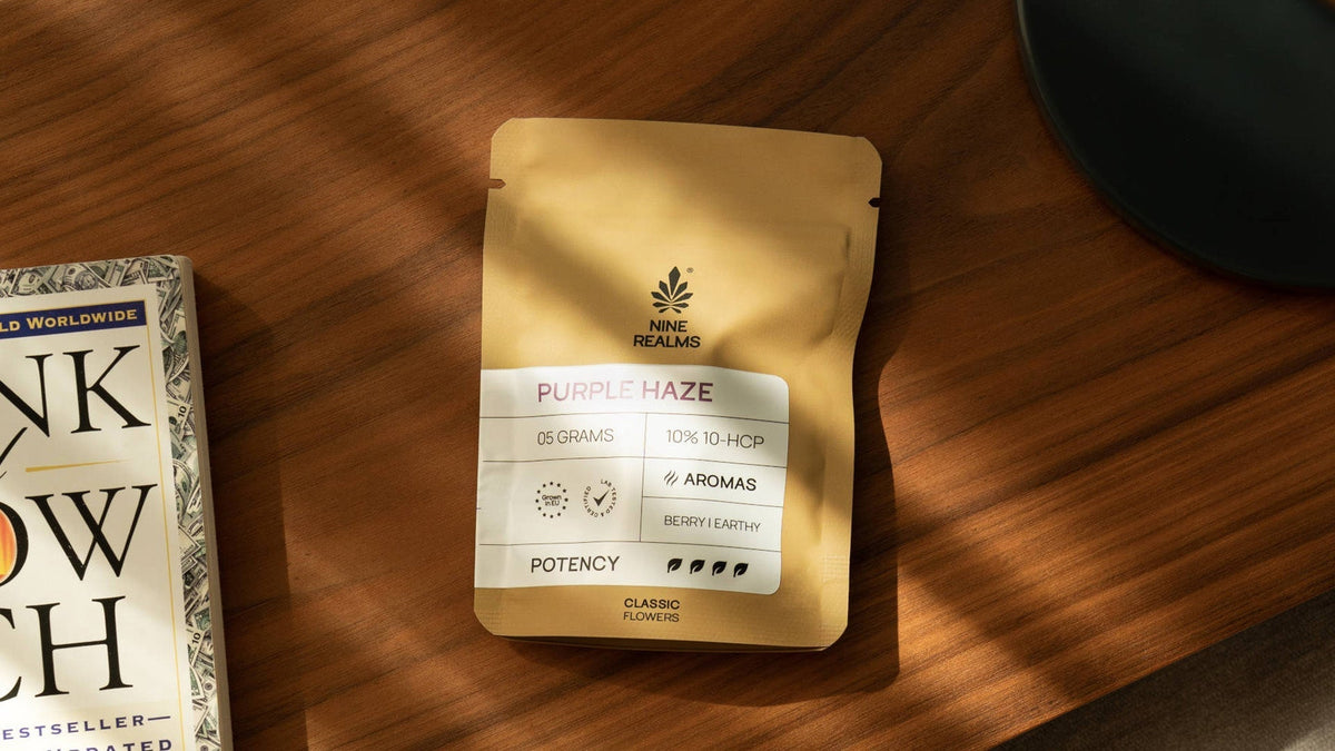 nine realms purple haze flower laying on the table with a book next to it